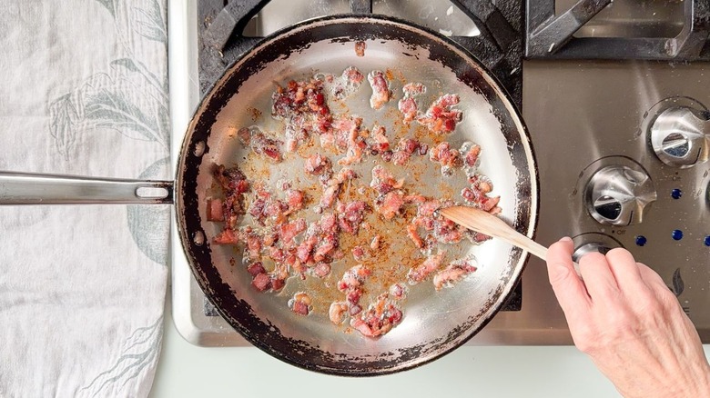 Cooking chopped bacon in skillet on stovetop