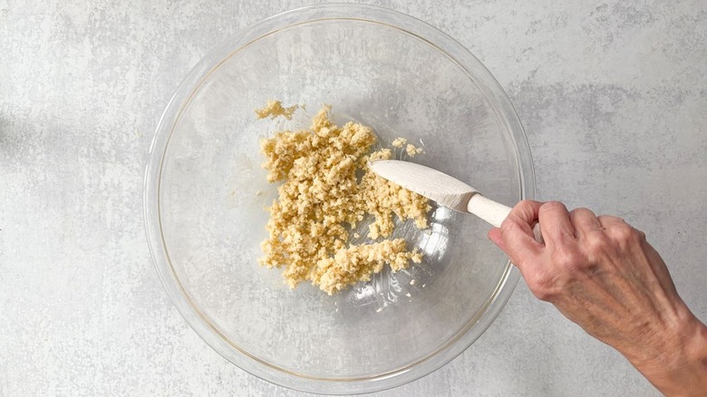 Mixing panko and heavy cream together in large glass bowl with wooden spoon