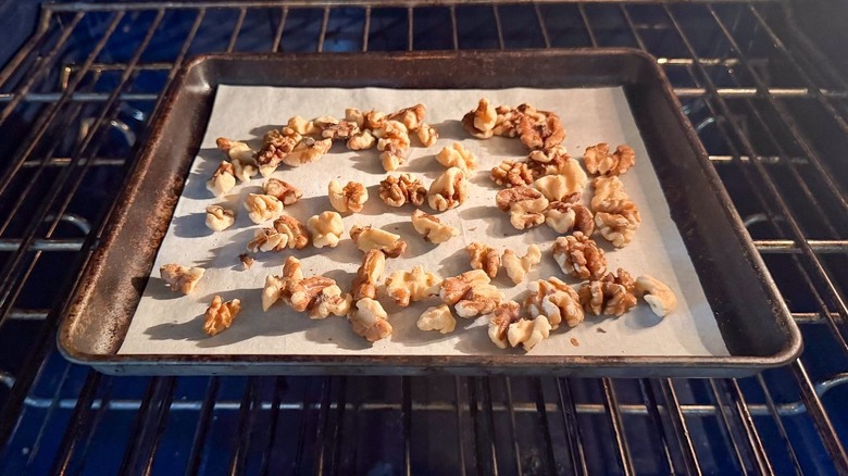 Walnuts toasting on parchment-lined baking sheet in oven