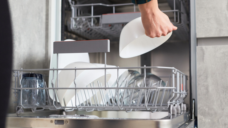 Hand adding upside-down bowl to dishwasher