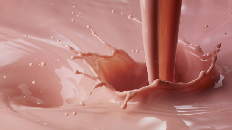A closeup of strawberry milk being poured into more strawberry milk