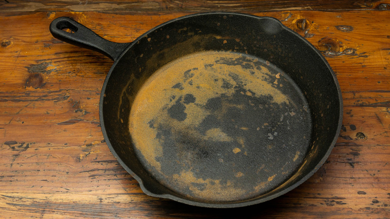 A rusty cast iron skillet on a wooden table