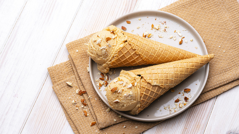 Two ice cream cones on a plate sprinkled with chopped almonds