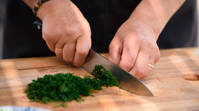 Hands chopping herbs on a cutting board