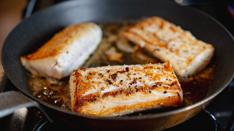 Seasoned fish fillets cooking in a pan