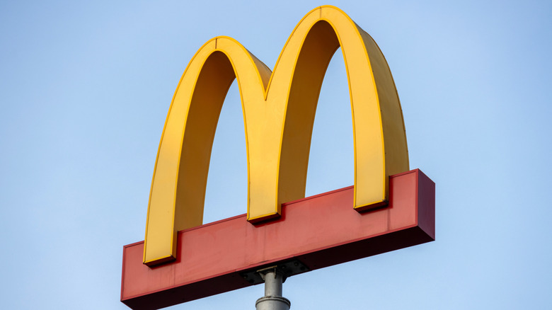The sun peeks behind a McDonald's sign outside a restaurant