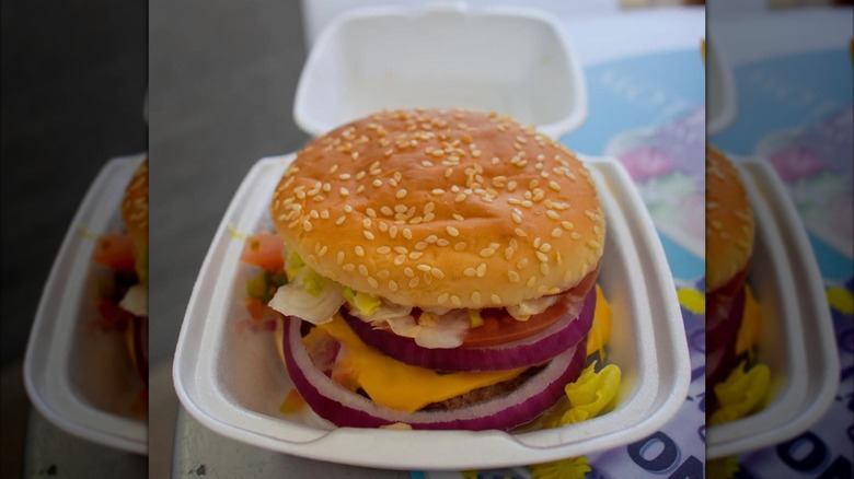 A cheeseburger in a styrofoam container