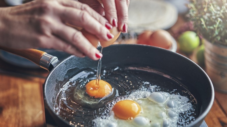 a person frying two eggs in a skillet