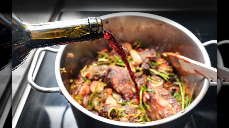 red wine poured over food in a stainless steel pot