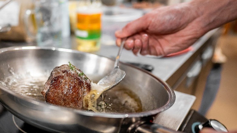 a chef cooking meat in a skillet