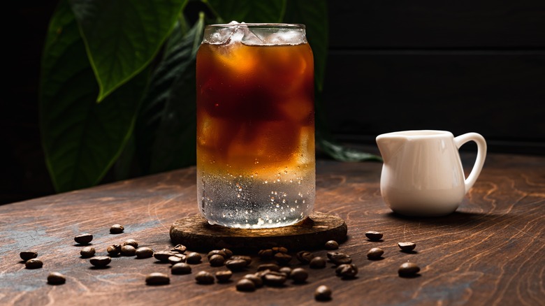 Glass of soda surrounded by coffee beans