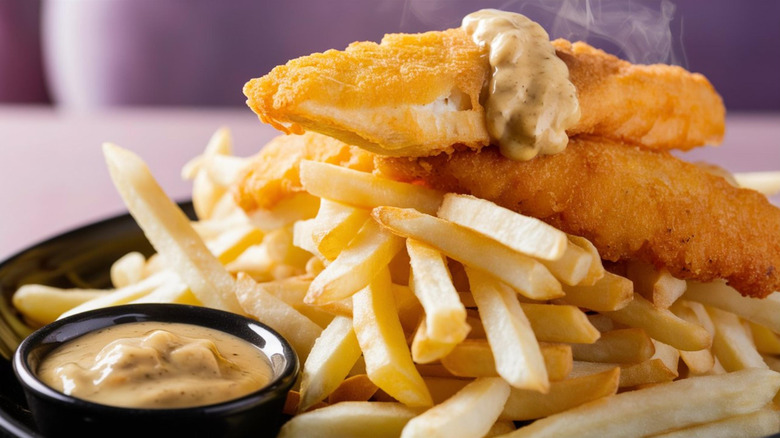 Steaming plate of fish and chips with sauce