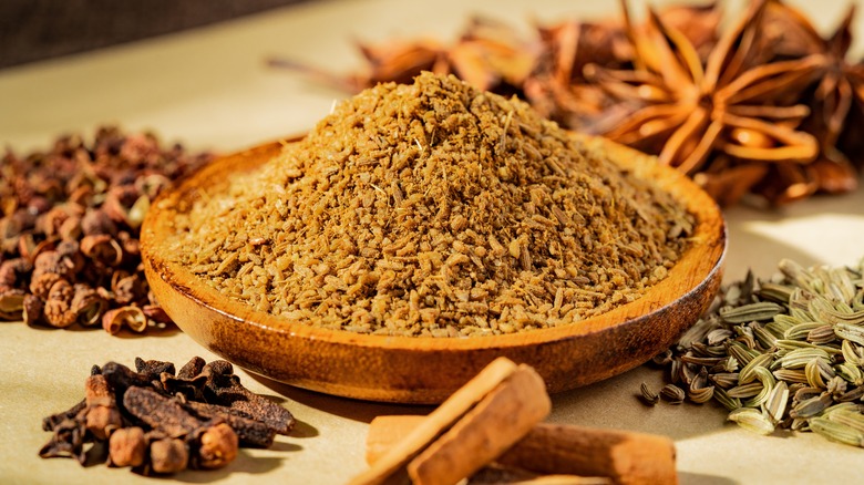 Pile of five-spice powder in a dish surrounded by spices