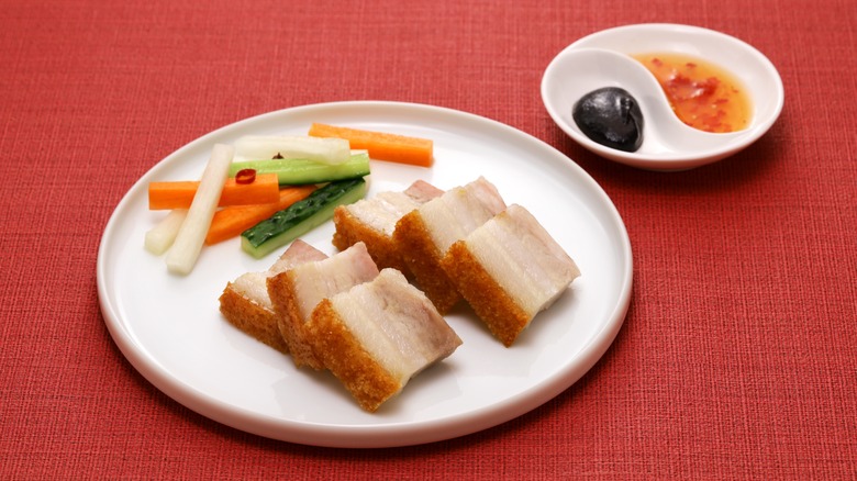pork belly with cucumber and carrot batons on a plate