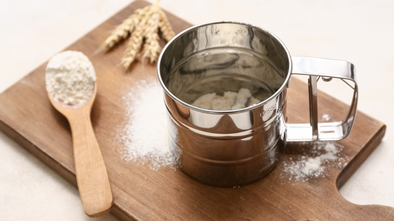 Metal flour sifter on cutting board