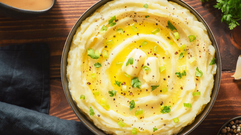 mashed potatoes in a bowl with butter and herbs and butter on top.