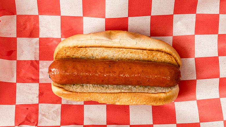 A hot dog in a bun on a checkered paper