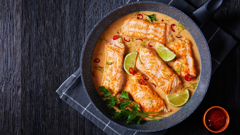 Poached coconut salmon in a pan