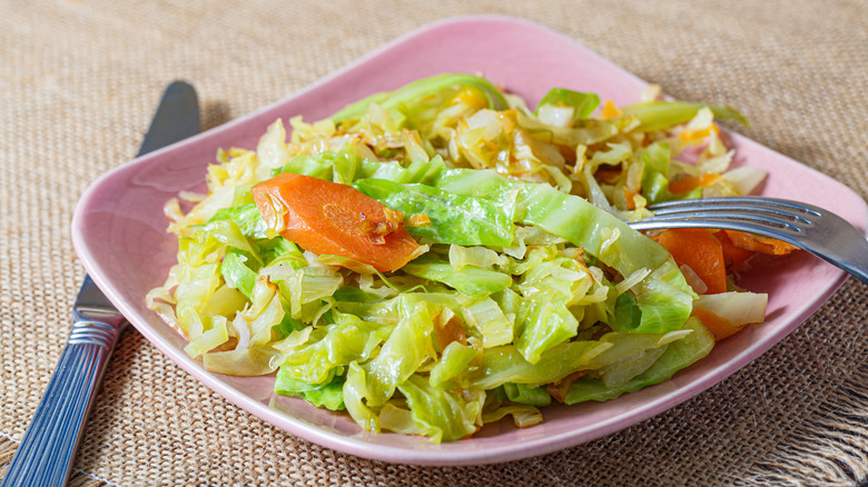 Cooked cabbage and carrots on pink plate