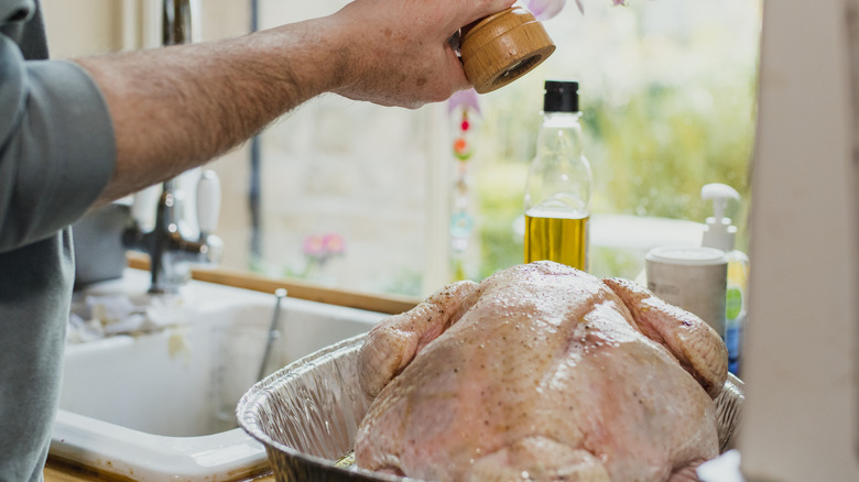 Close up shot of a man's hands as he seasons a turkey ready for Thanksgiving dinner.