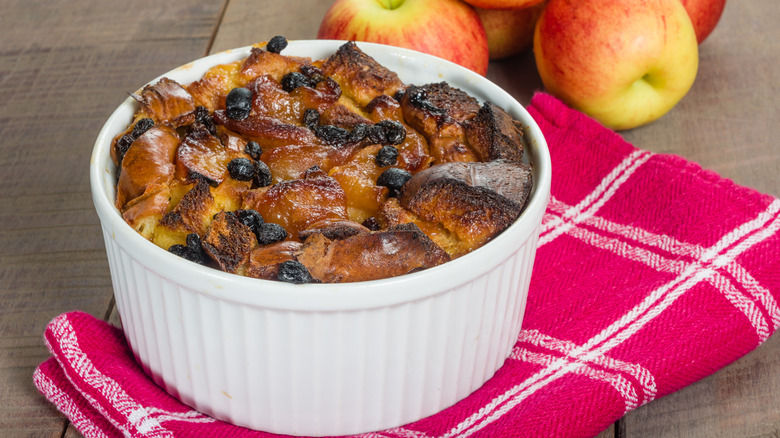 Bread pudding in casserole dish with apples and linen napkin