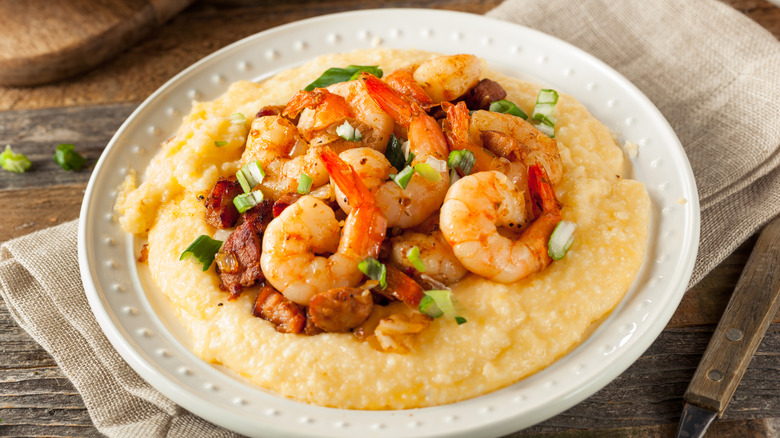 shrimp and grits in white bowl on rustic table with napkin
