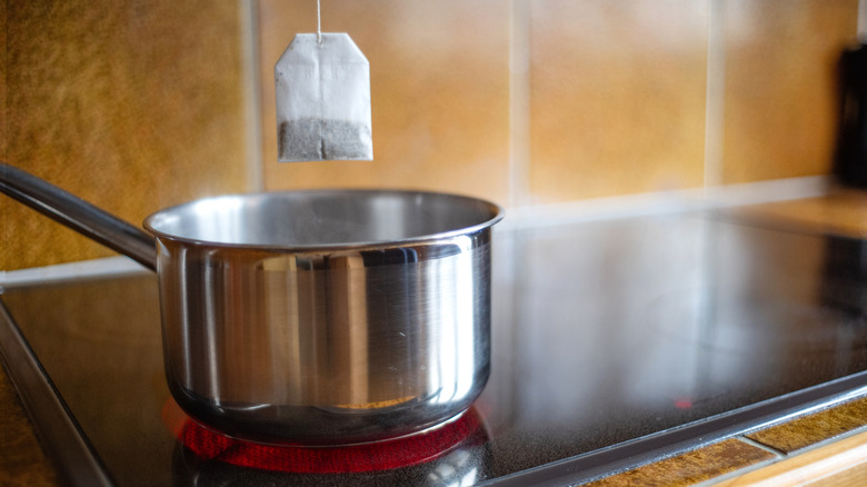 A tea bag hands over a pot on a stovetop