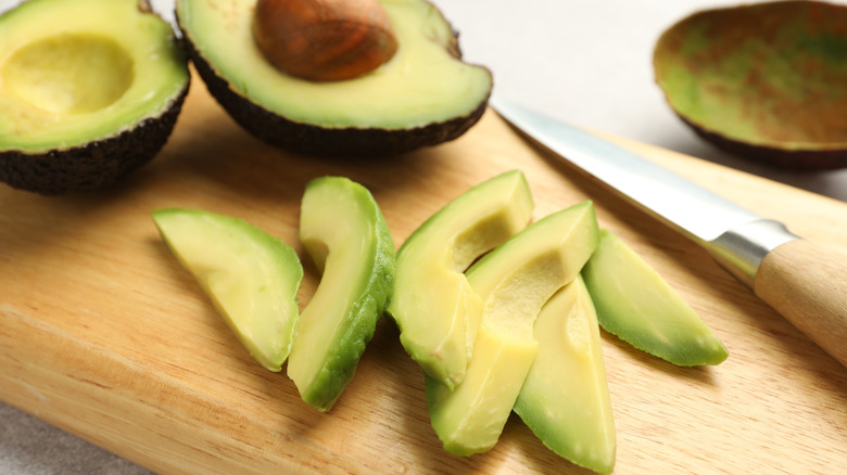 Sliced avocado on wood board