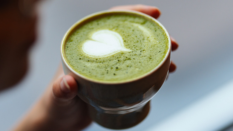 Woman holding a cup of matcha with white heart