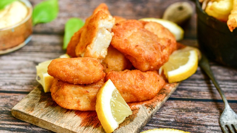 fried fish on a wooden board with lemons