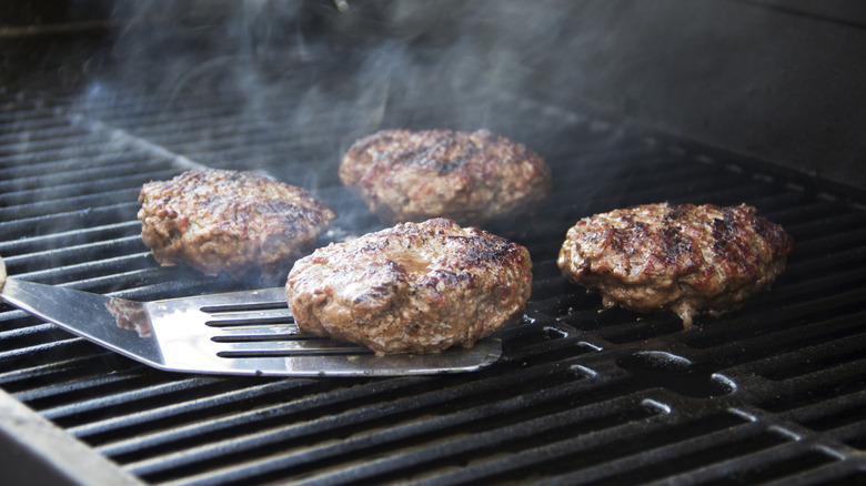Patties on a grill with a spatula sliding under one