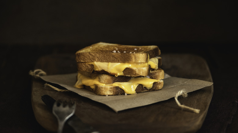 Two grilled cheese sandwiches stacked on wooden board