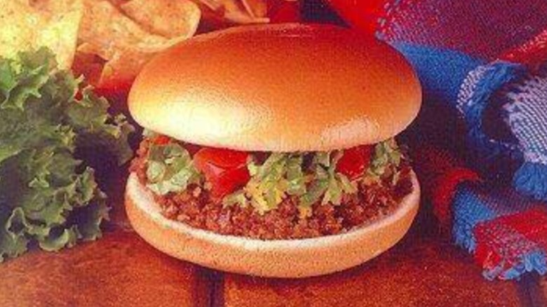 Taco Bell Bell Beefer Burger beside lettuce and tablecloth