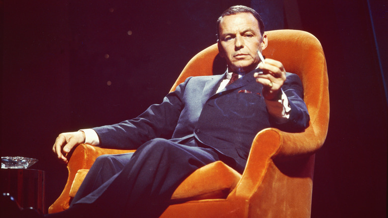 Frank Sinatra posing in orange armchair with cigarette