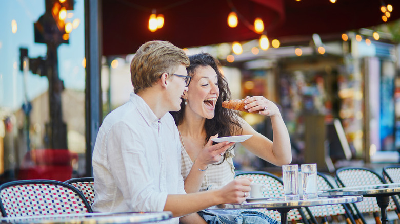 Happy couple eating croissant