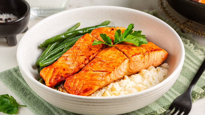 Two cooked salmon filets over rice with green beans