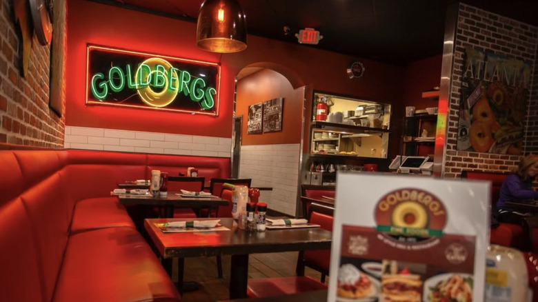 The interior of a Goldberg's, including a neon sign and red bench seating
