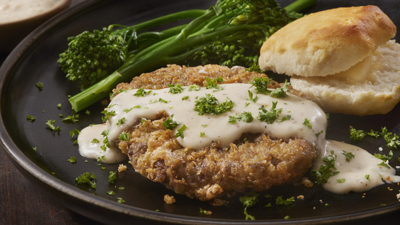 Chicken fried steak, served with a biscuit and broccoli
