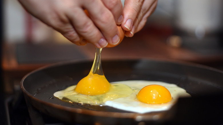 cracking eggs into frying pan