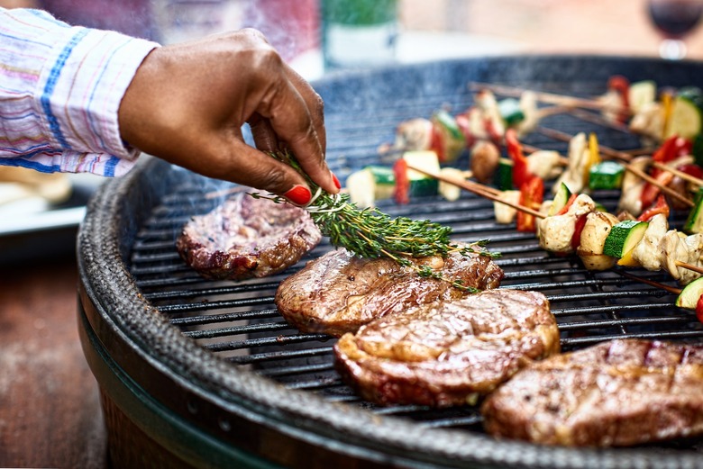 The Daily Meal's Ultimate Grilling Guide - black manicured hand grills steak and veggie kebabs