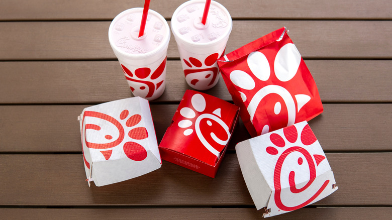 Three Chick-fil-A takeout boxes alongside a takeout bag and two to-go cups