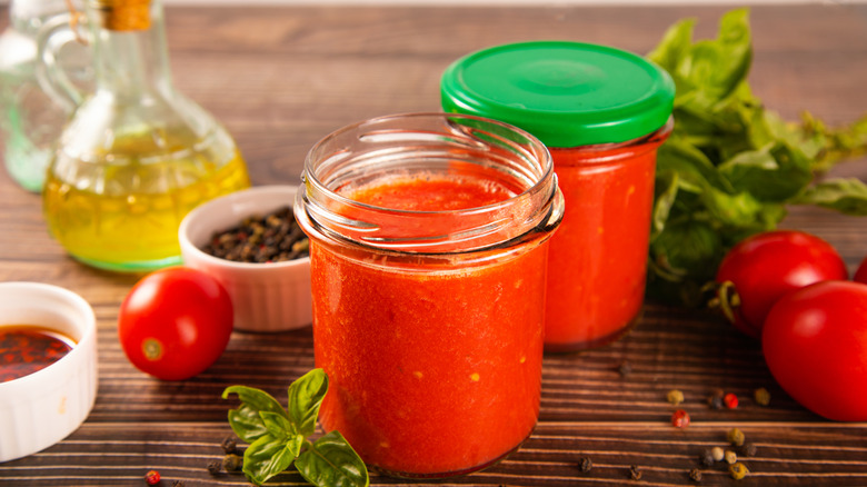 Jars of tomato sauce with oil and herbs