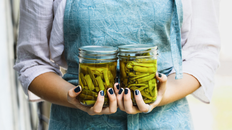 Woman holding two Mason jars filled with pickled vegetables