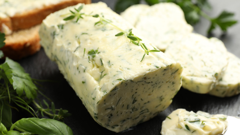 Fresh herb compound butter sliced next to herbs