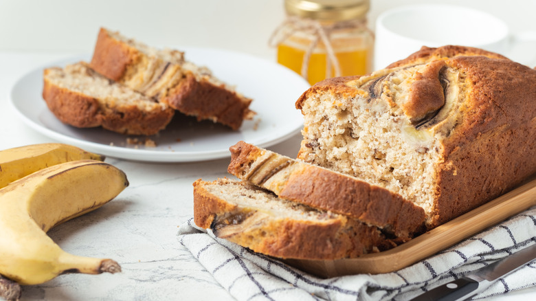 banana bread on a wooden tray next to bananas