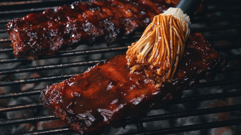 brushing barbecue sauce on ribs