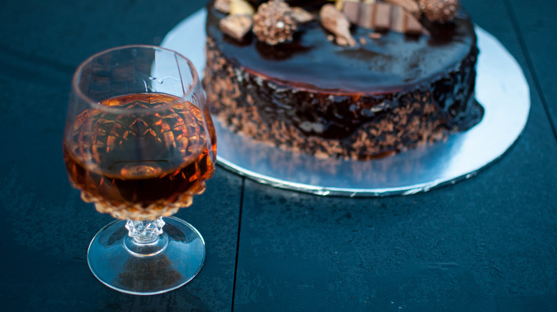 Glass of cognac with chocolate cake in background