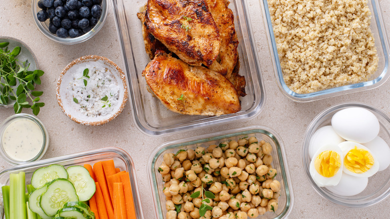 Overview of protein foods like chicken, chickpeas, quinoa, and eggs in glass containers.