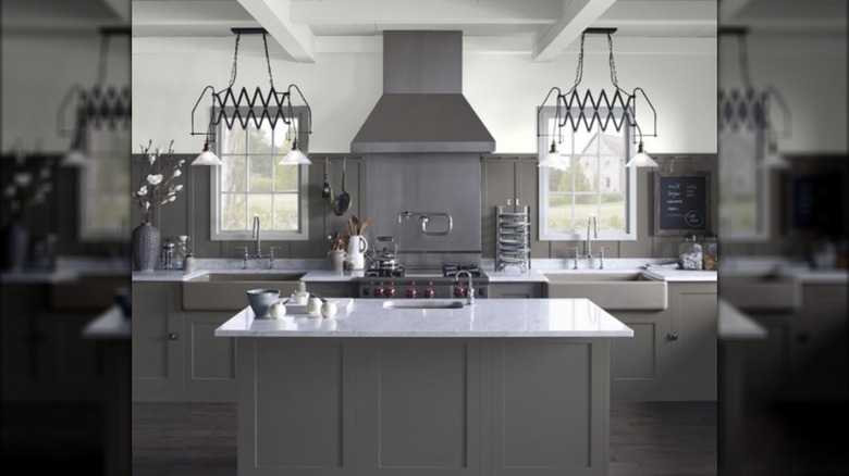 dramatic dark grey kitchen with funky black light fixtures and windows on both sides of the stove.