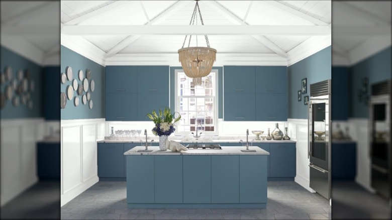 classic blue painted kitchen with a beight pendant light and white woodworking ceilings.